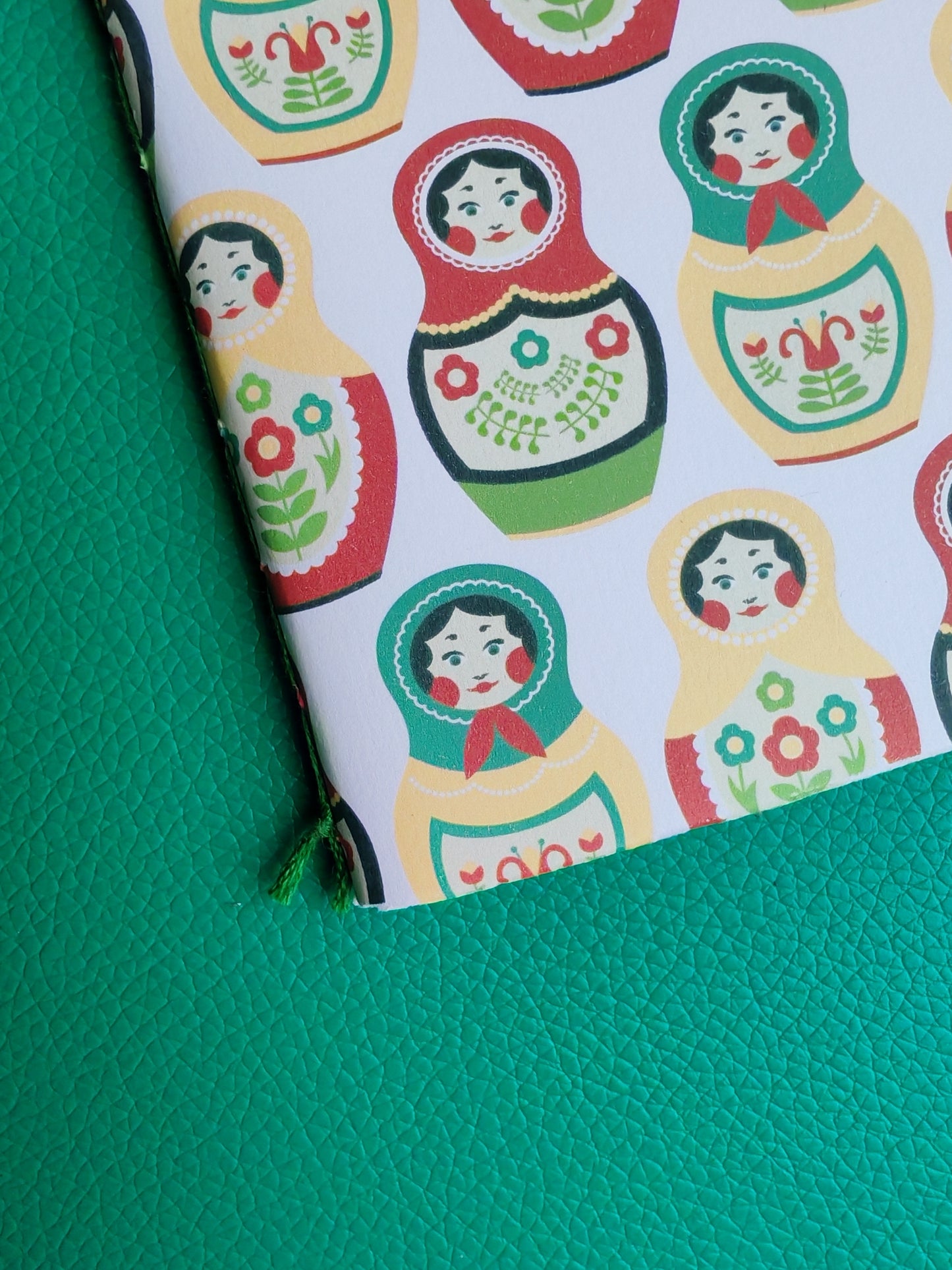 Close up of notebook with Russian matryoshka doll pattern on a green surface