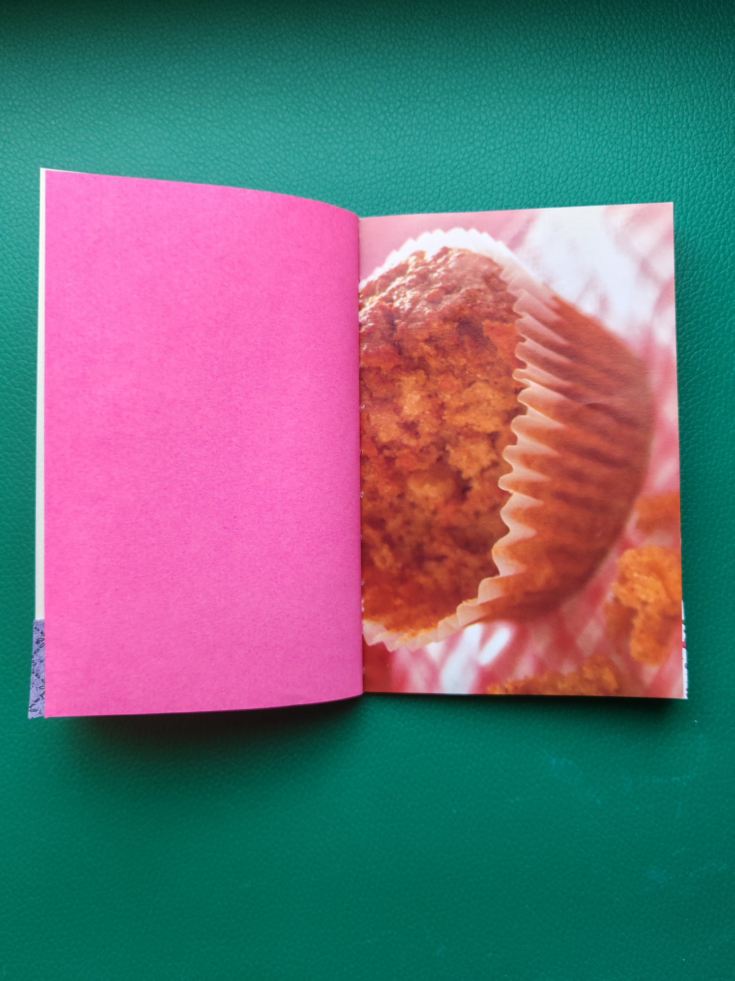 Open book with a pink page and a muffin image on a green background