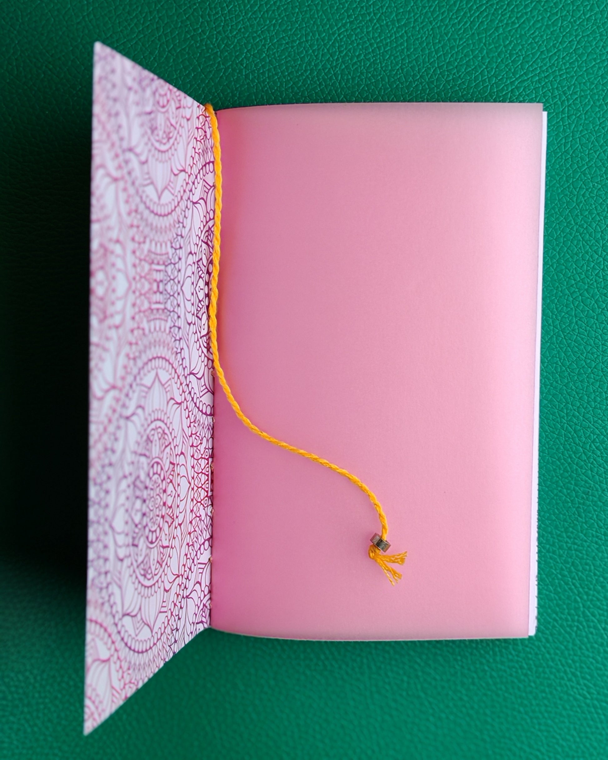 Open notebook showing details of inner flyleaf in pink with yellow bookmark