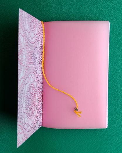 Open notebook showing details of inner flyleaf in pink with yellow bookmark