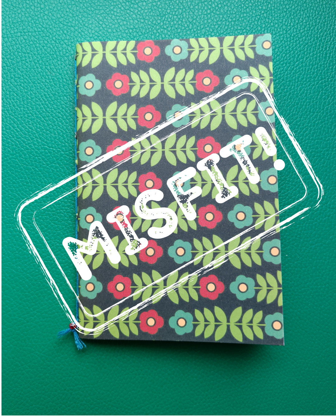 Notebook with floral pattern and 'MISPIT' text on a green background