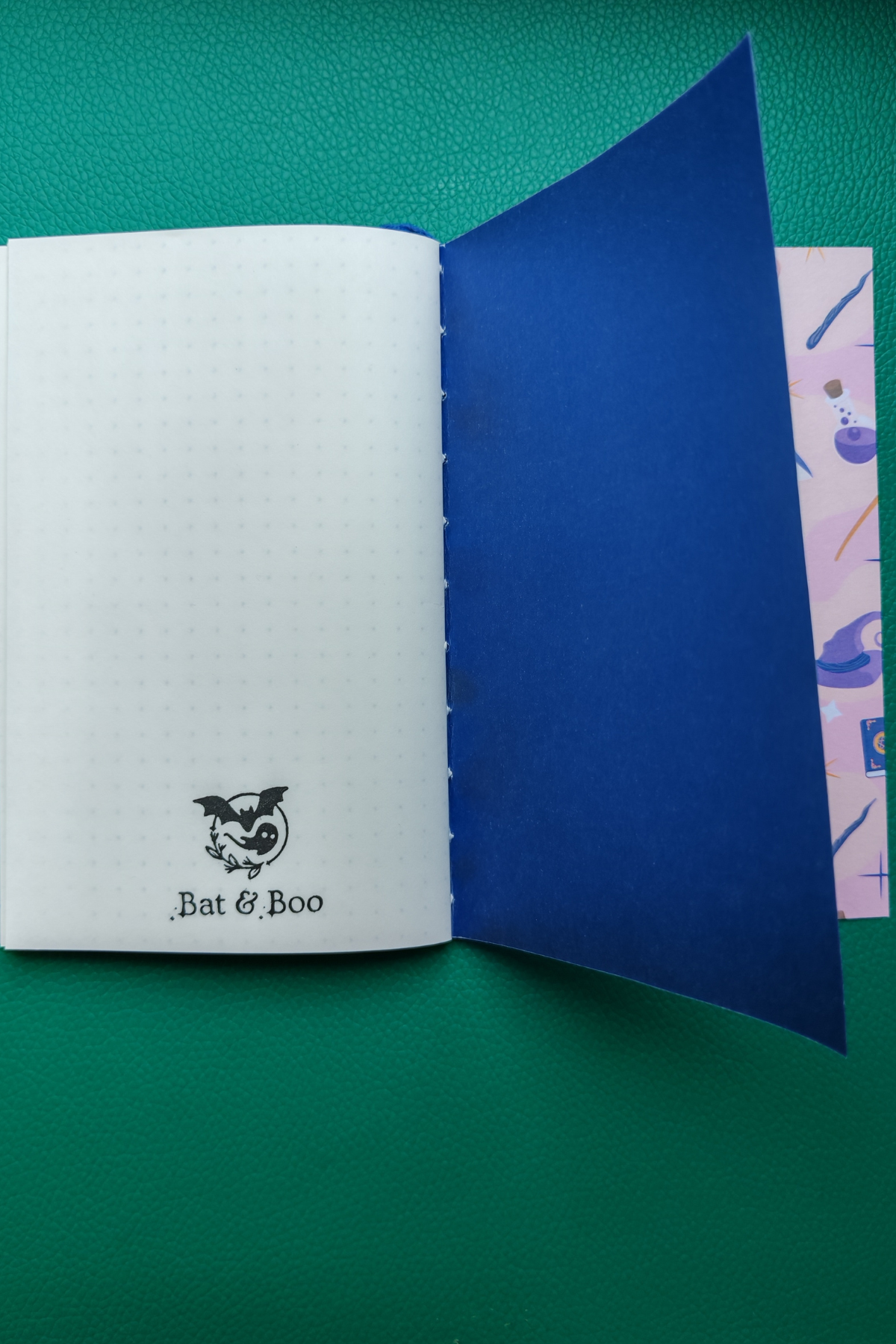 Open notebook with blue endpage and white pages featuring 'Bat & Boo' logo on a green background