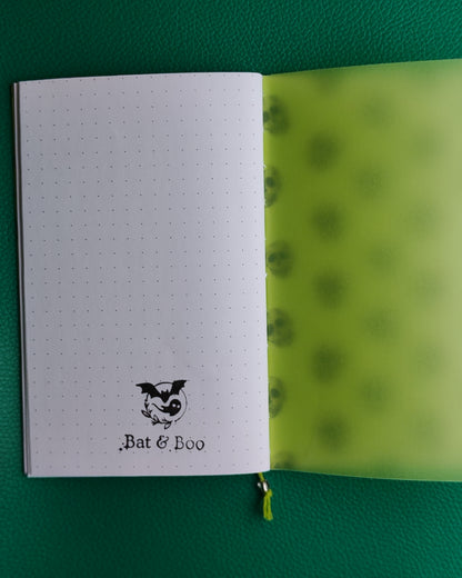 Open notebook with dotted pages and green interior on a green background, showing business logo stamped on final page