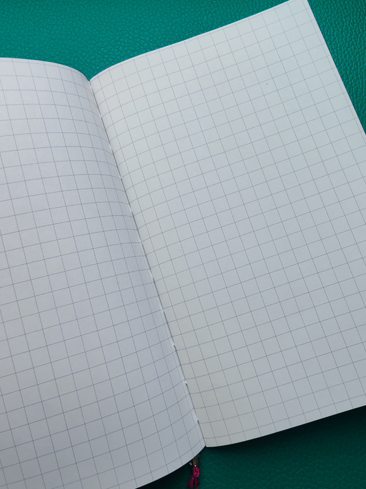 Open notebook with grid paper on a green surface