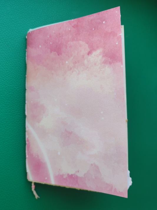 Pink notebook with cloud pattern on a green background