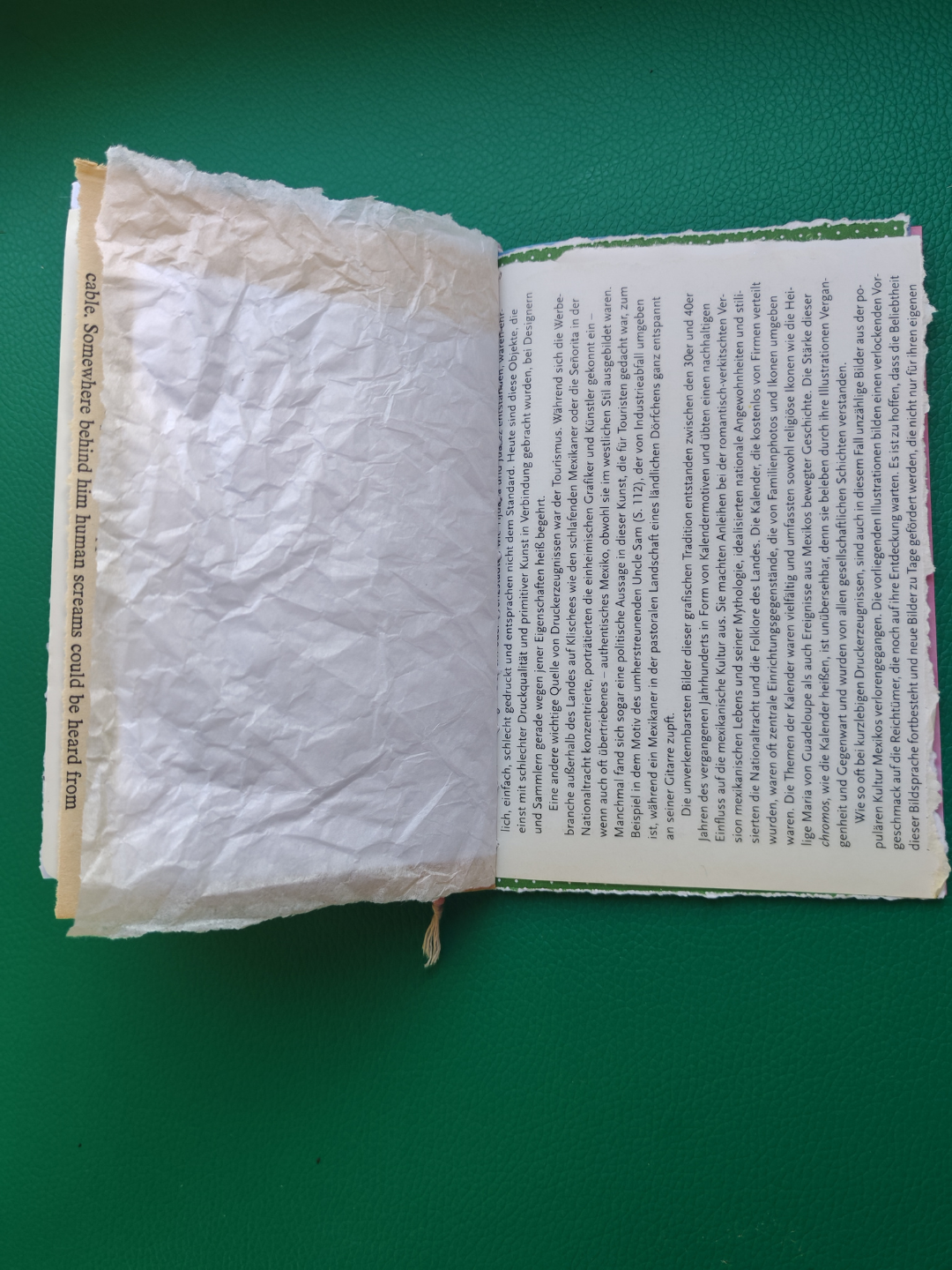 Open book with one page made of textured paper and the other page with printed text on a green background