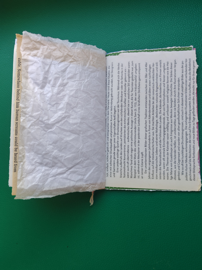 Open book with one page made of textured paper and the other page with printed text on a green background
