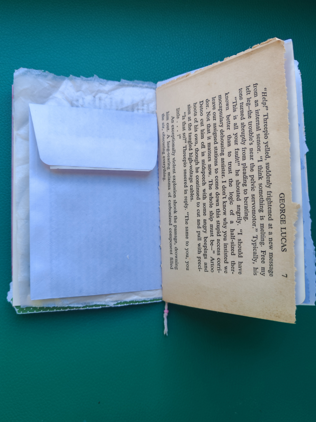 Open book with a white envelope inside on a green background