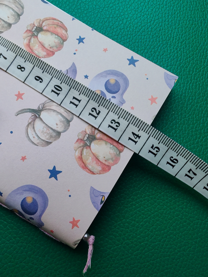 Notebook with pumpkin design on cover, partially open, with a ruler on top.