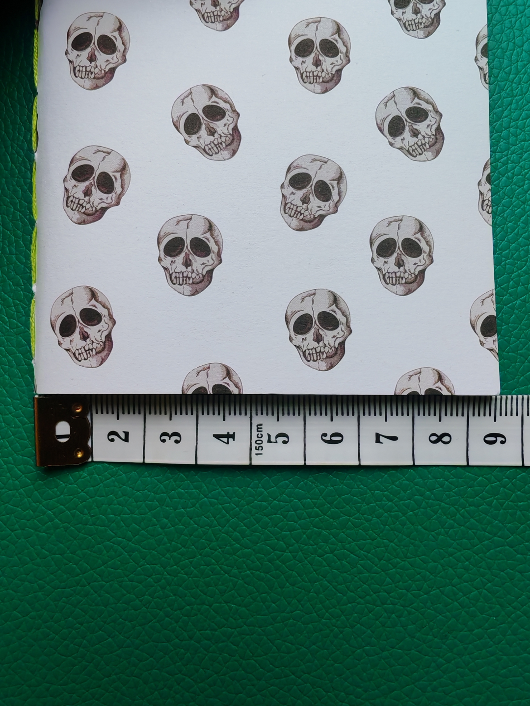 Fabric with skull pattern on a white background, measured against a ruler.