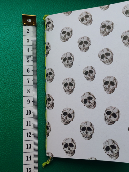 Notebook with skull pattern on a green background next to measuring tape