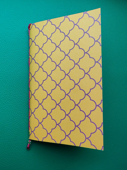 Notebook with yellow cover featuring a purple pattern on a green background