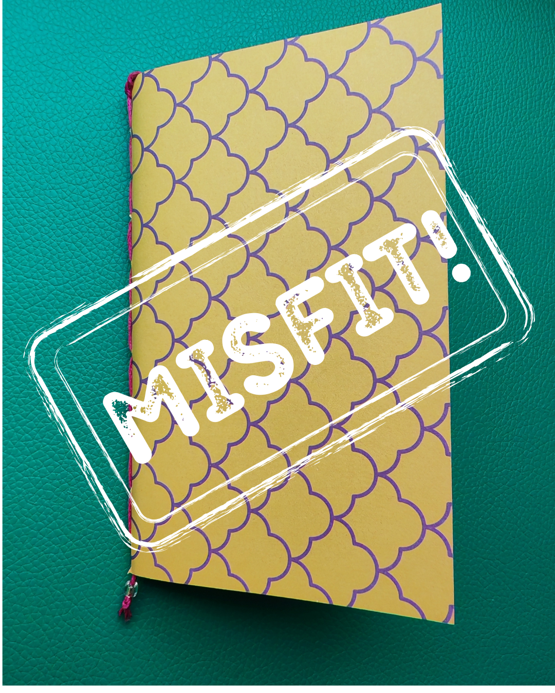 Notebook with a patterned cover and 'MISFIT!' text on a teal background
