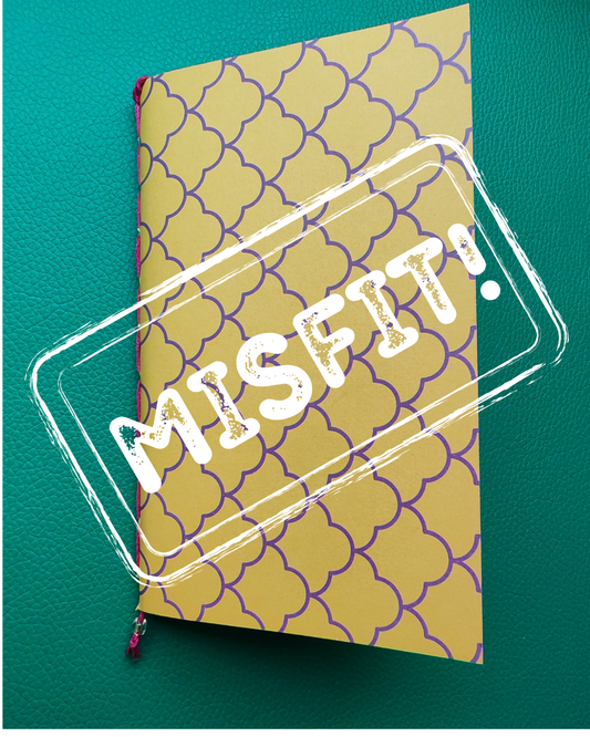 Notebook with a patterned cover and 'MISFIT!' text on a teal background