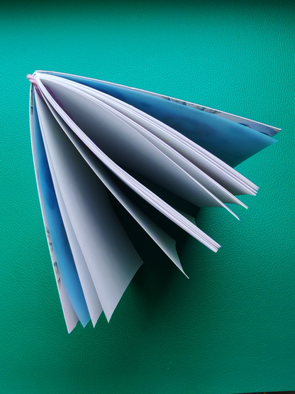 Open book with blue endpages and plain white paper on a green background