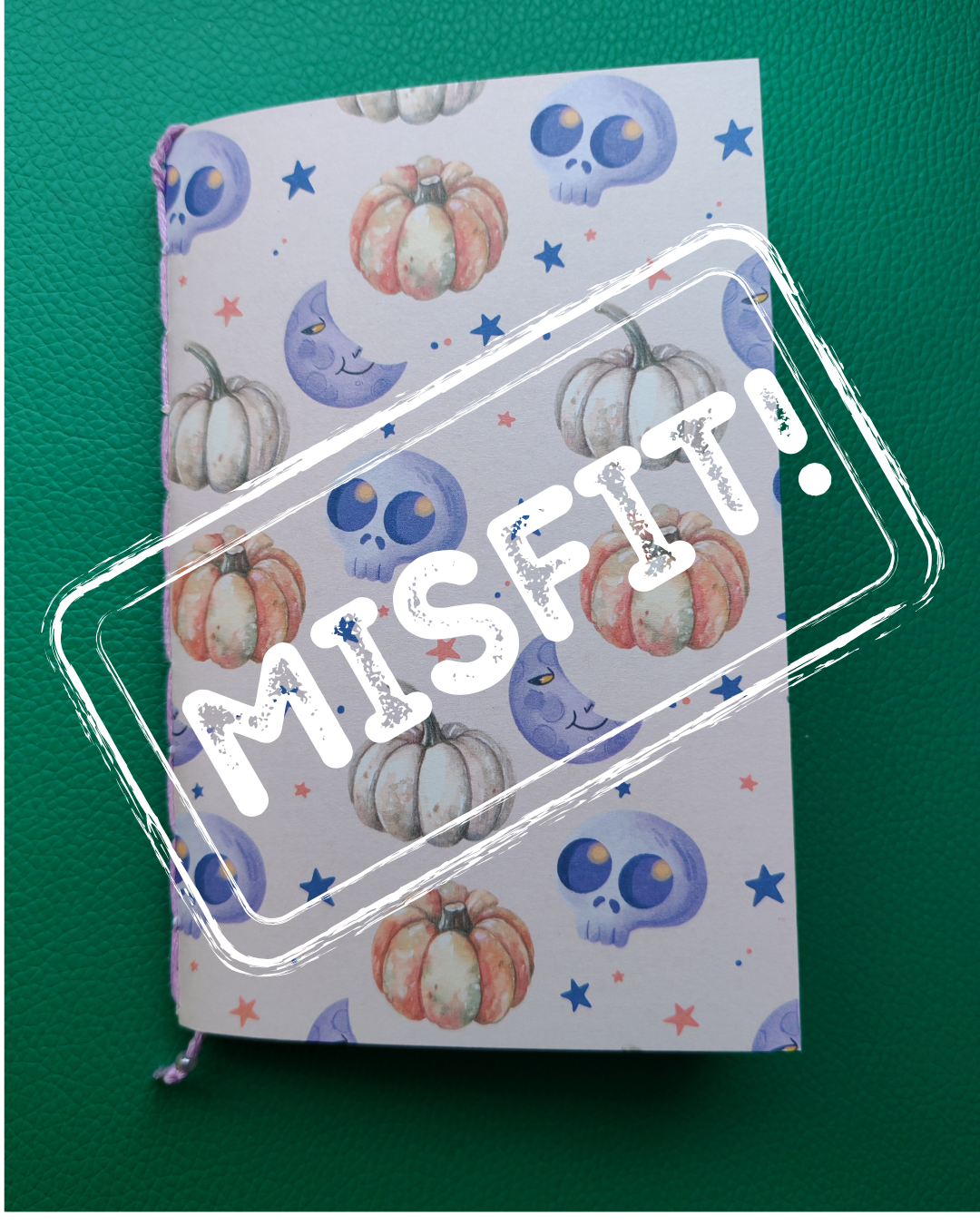 Notebook with Halloween-themed cover featuring pumpkins and skulls on a green background, with 'Misfit' stamp.