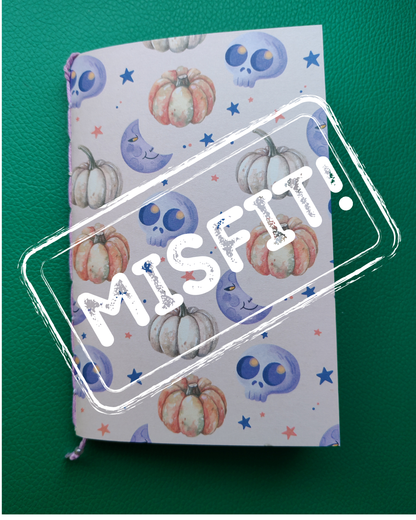 Notebook with Halloween-themed cover featuring pumpkins and skulls on a green background, with 'Misfit' stamp.