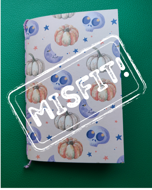 Notebook with Halloween-themed cover featuring pumpkins and skulls on a green background, with 'Misfit' stamp.