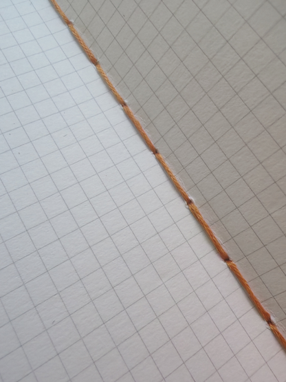 Grid paper close up with stitched binding down centre
