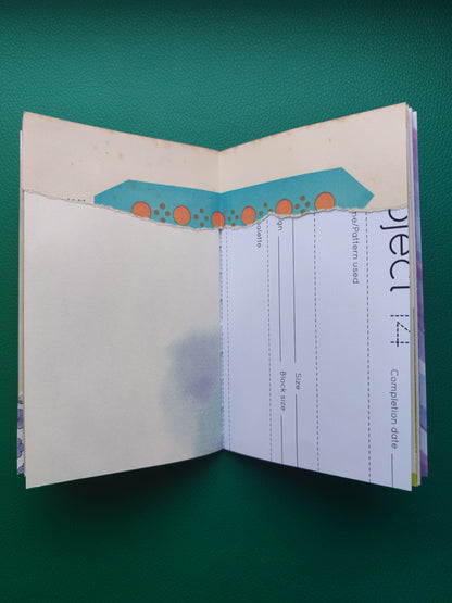 Open notebook with patterned paper and embellishment on a green background
