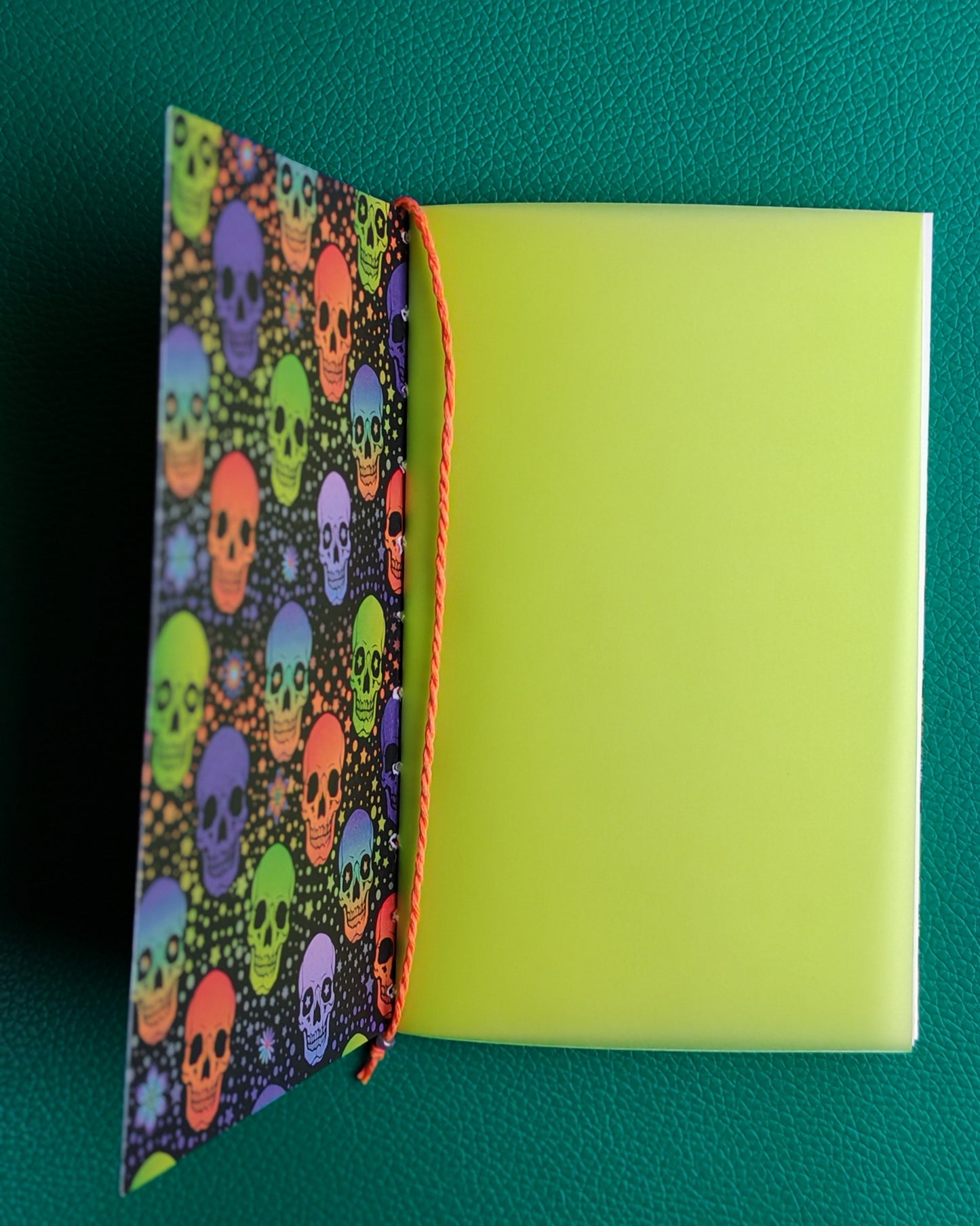 Notebook with colorful skull pattern on the cover against a green background