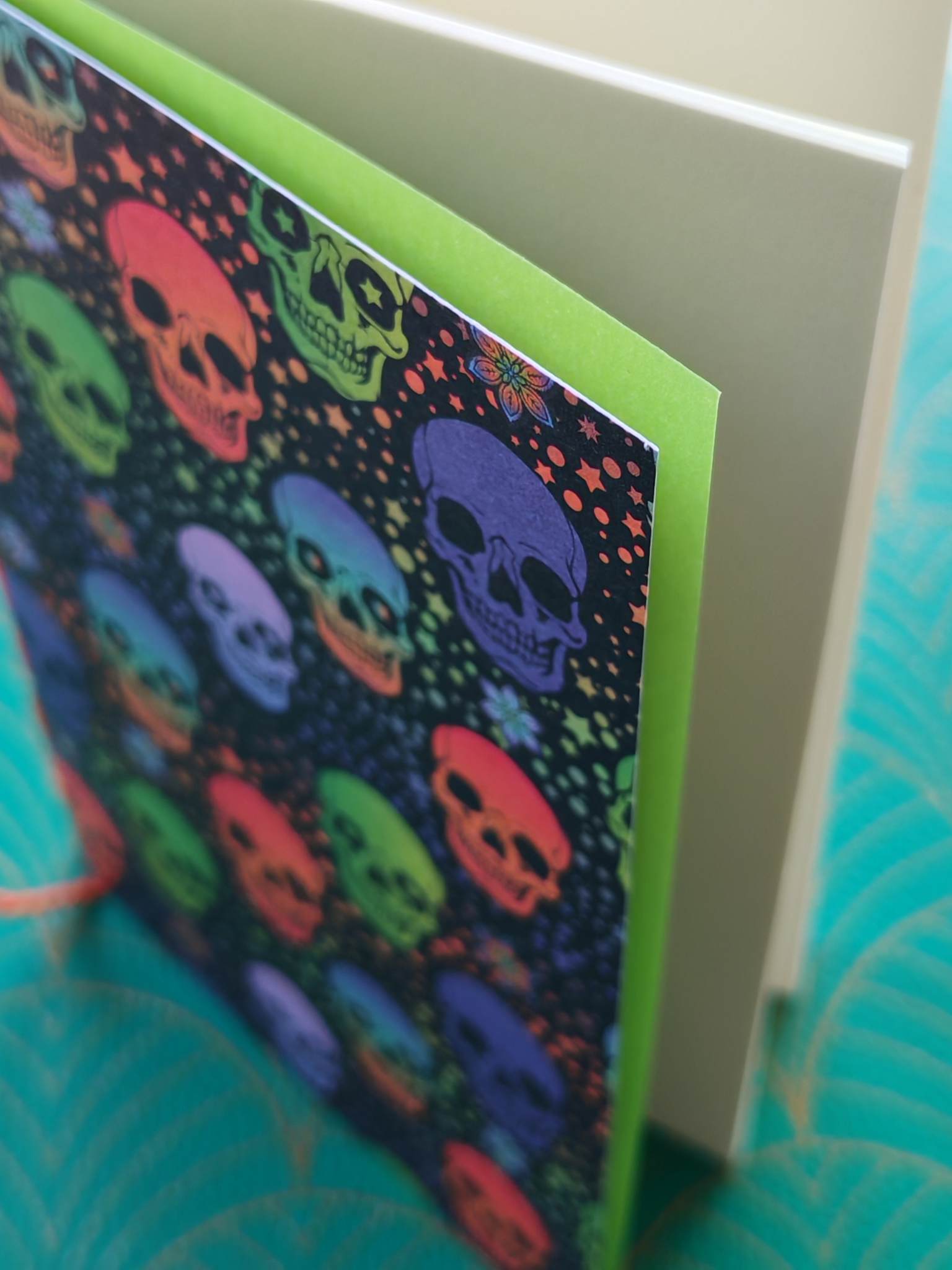 notebook with colourful skull pattern cover, propped open to show acid green flyleaf against creamy paper