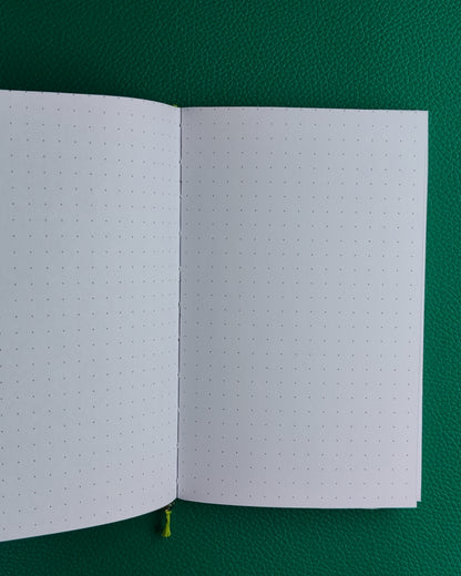 Open notebook with dot grid paper on a green background