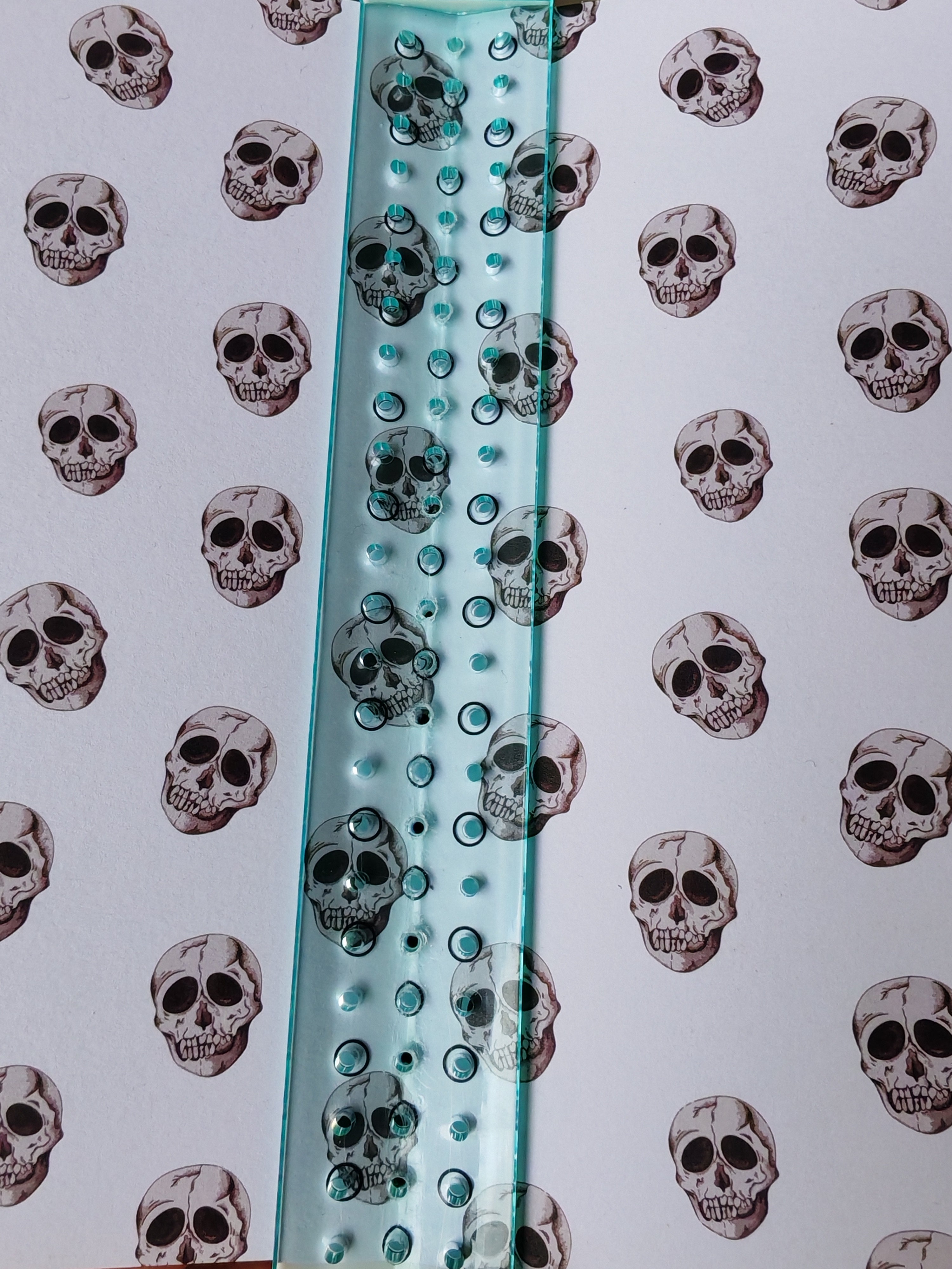 Skull patterned cardstock held in book binding awl