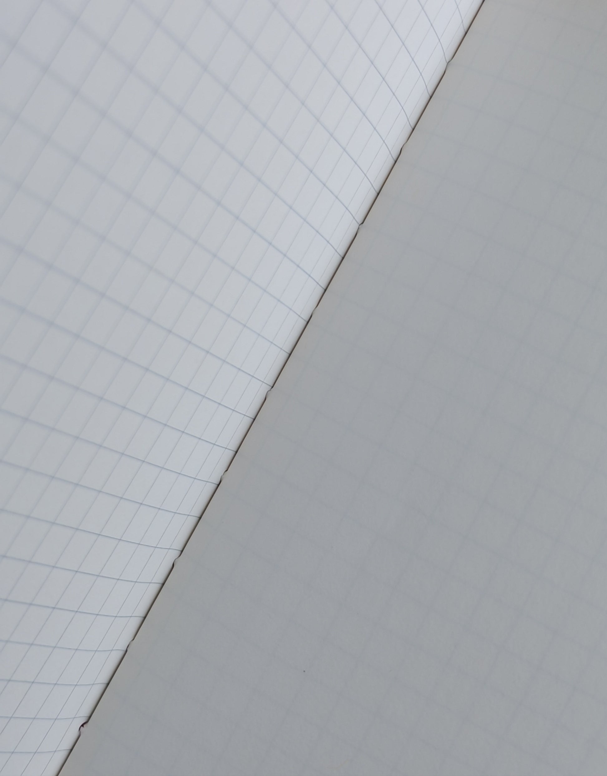 Two pages meeting at the fold, one with grid lines and the other plain white