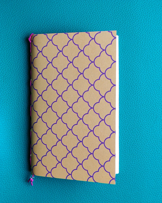 Notebook with purple scallop pattern on yellow cover against a blue background