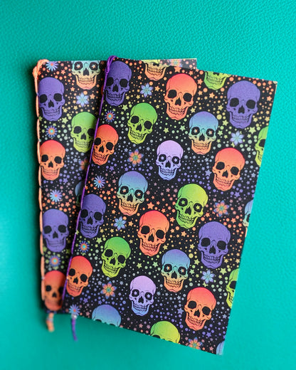 Colorful skull patterned travelers notebook inserts on a teal background